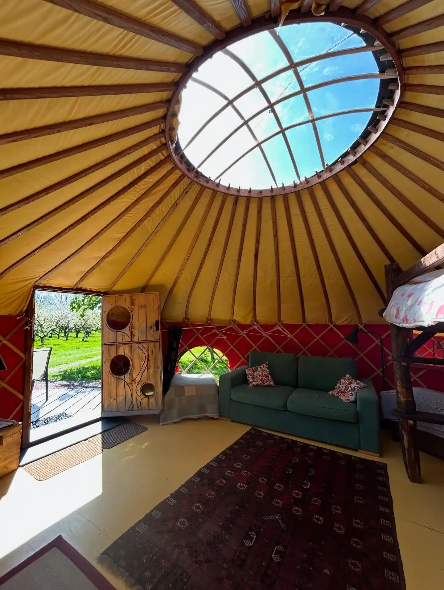 17 Yurt Living Ideas for a Cozy Off-Grid Lifestyle 8 7. Red Lattice Walls and a Green Sofa