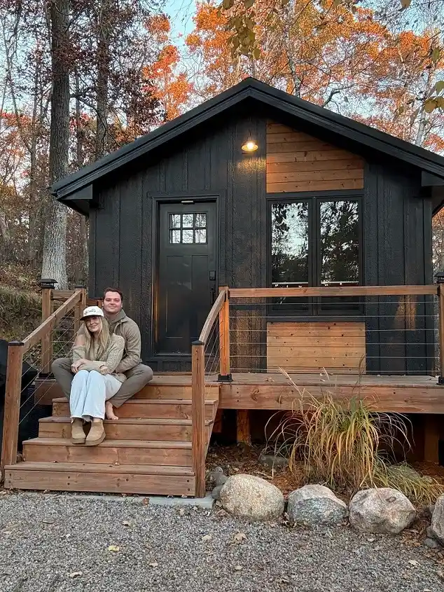 15 Tiny House Ideas for Couples Who Live Small Full-Time 9 8. Charcoal Cabin With a Warm Wood Entry Deck