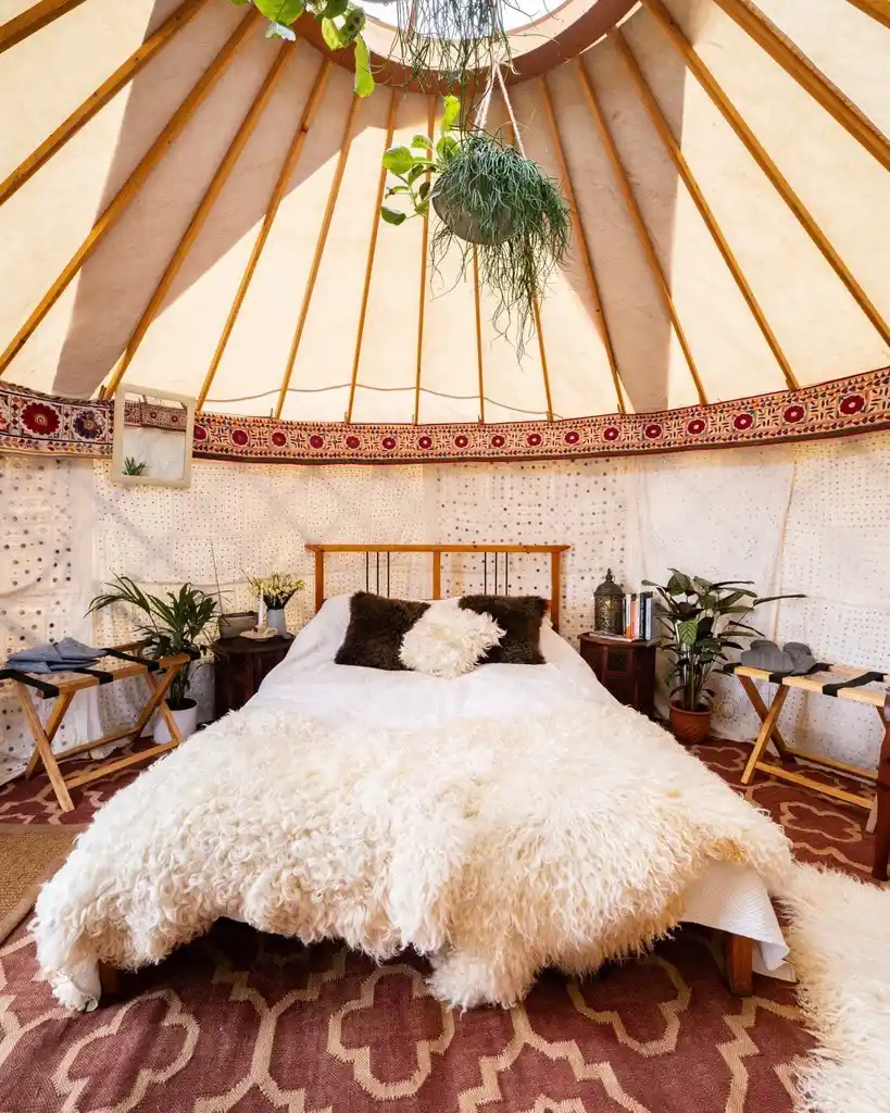 17 Yurt Living Ideas for a Cozy Off-Grid Lifestyle 18 17. A Sheepskin Bed Under Hanging Plants