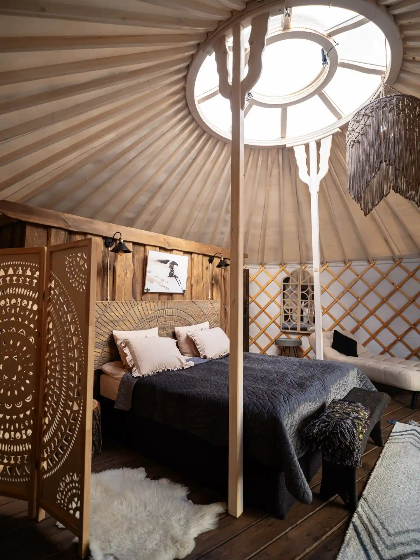 17 Yurt Living Ideas for a Cozy Off-Grid Lifestyle 11 10. A Carved Screen and Charcoal Bedding on Dark Planks